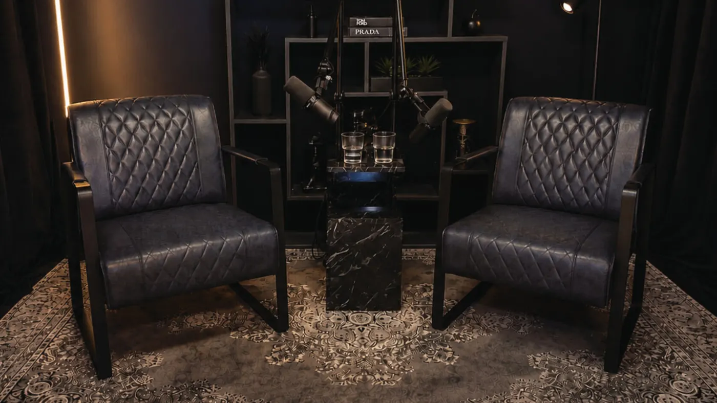 Studio-Set Smoke: zwei dunkelblaue Ledersessel mit Mikrofonen und Marmortisch vor dunklem Regal