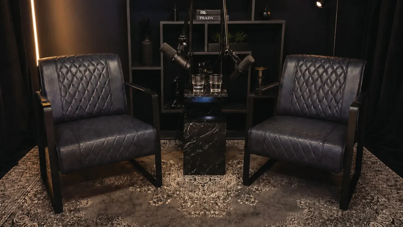 Studio-Set Smoke: zwei dunkelblaue Ledersessel mit Mikrofonen und Marmortisch vor dunklem Regal